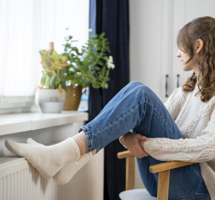 Femme assise à côté d'un radiateur